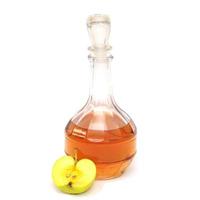 A decanter with apple cider vinegar and half a green apple isolated on a white background. photo