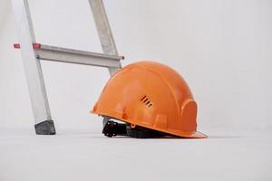 Construction helmet is lying next to stepladder against plaster wall. photo