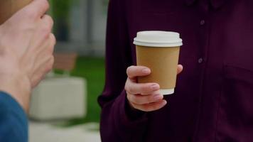 Cerrar la mano de una mujer de negocios sosteniendo un café y hablando con alguien. video