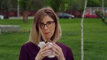 Hungry woman eating while looks in camera. video