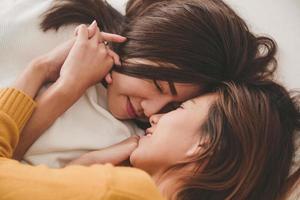 Beautiful young asian women LGBT lesbian happy couple hugging and smiling while lying together in bed under blanket at home. Funny women after wake up. LGBT lesbian couple together indoors concept. photo