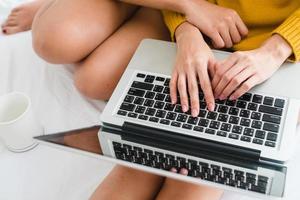 Beautiful young asian women LGBT lesbian happy couple sitting on bed hug and using laptop computer together bedroom at home. LGBT lesbian couple together indoors concept. Spending nice time at home. photo