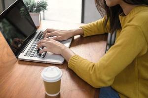 Business Technology Concepts - Digital lifestyle working outside office. Woman hands typing laptop computer with blank screen on table in coffee shop. Blank laptop screen mock up for display of design photo