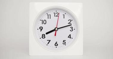 vista frontal, lapso de tiempo, el despertador blanco muestra el correr del tiempo. sobre el fondo blanco.