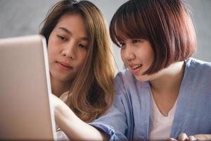 Two young business women sitting at table in cafe. Asian women using laptop and cup of coffee. Freelancer working in coffee shop. Working outside office lifestyle. One-on-one meeting. photo