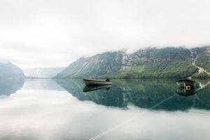 lonely boats calm lake with misty mountain background photo