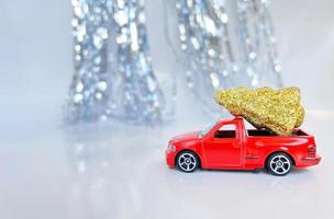 red car carrying a Christmas tree - banner with place for text. festive shiny background for christmas photo
