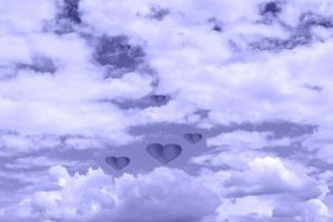 nubes blancas hinchadas con corazones. Fondo abstracto de cielo nublado en tonos muy peri foto