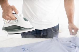 man steaming clothes with clothing iron photo