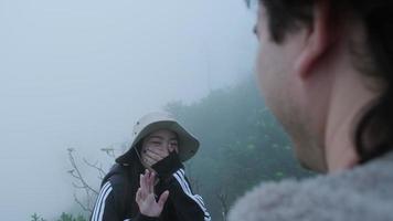 un couple de jeunes voyageurs heureux se détend dans les montagnes et attend de regarder le lever du soleil sur les falaises en hiver. concept de voyage et d'aventure. video