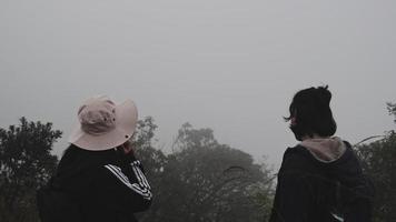 Couple of Young happy travelers relax in the mountains and wait to watch the sunrise on the cliffs in winter season. Travel and Adventure Concept. video