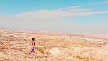 Young beautiful caucasian athlete woman running uphill on top mountain outdoors with scenic panorama. The athlete fit and firm girl exercising by jogging workout sport outdoor for her healthy wellness video