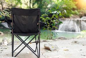 silla de camping vacía con fondo de cascadas. tiempo de relajación foto