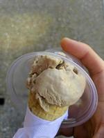 patrón de postre helado de sabor helado en taza blanca mano sujetando sobre la mesa. foto