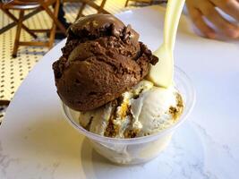 patrón de postre helado de sabor helado en taza blanca mano sujetando sobre la mesa. foto