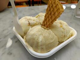 patrón de postre helado de vainilla sabor helado en cono de waffle mano sujetando sobre la mesa. foto