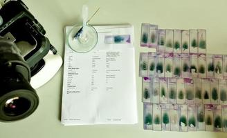 Hematological stained glass slide and report isolated on table with microscope in laboratory. photo