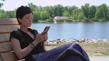 mujer escribiendo sms en el móvil al aire libre.