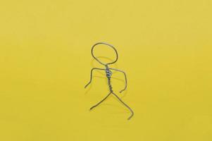 Metal man made of wire stands on yellow background photo