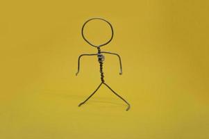 Metal man made of wire stands on yellow background photo