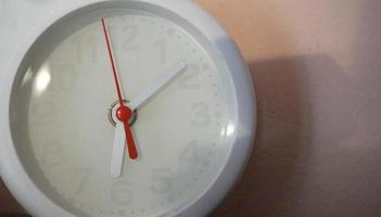 A closeup shot of a white clock with arrows showing time. photo