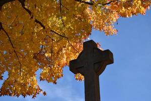 A cross in a cemetery in the fall photo