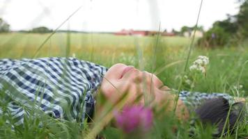 gros plan une femme asiatique heureuse se reposant sur l'herbe dans une ferme. prendre une grande inspiration et prendre l'air. se sentir frais et avoir un visage heureux. être dans une belle ferme verte video