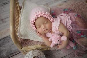 Little baby enveloped in pink clothes with a bandage on his head lies sleeps on white pillow photo