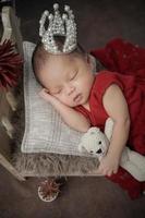 Little baby covered in red clothes with bandage on his head lying sleeping on white pillow photo