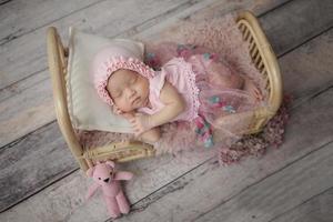 Pequeño bebé envuelto en ropa rosa con un vendaje en la cabeza yace duerme sobre una almohada blanca foto