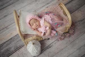 Little baby enveloped in pink clothes with a bandage on his head lies sleeps on white pillow photo