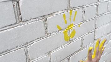 kinderen tekenen verf op handen en laten sporen achter op de muur