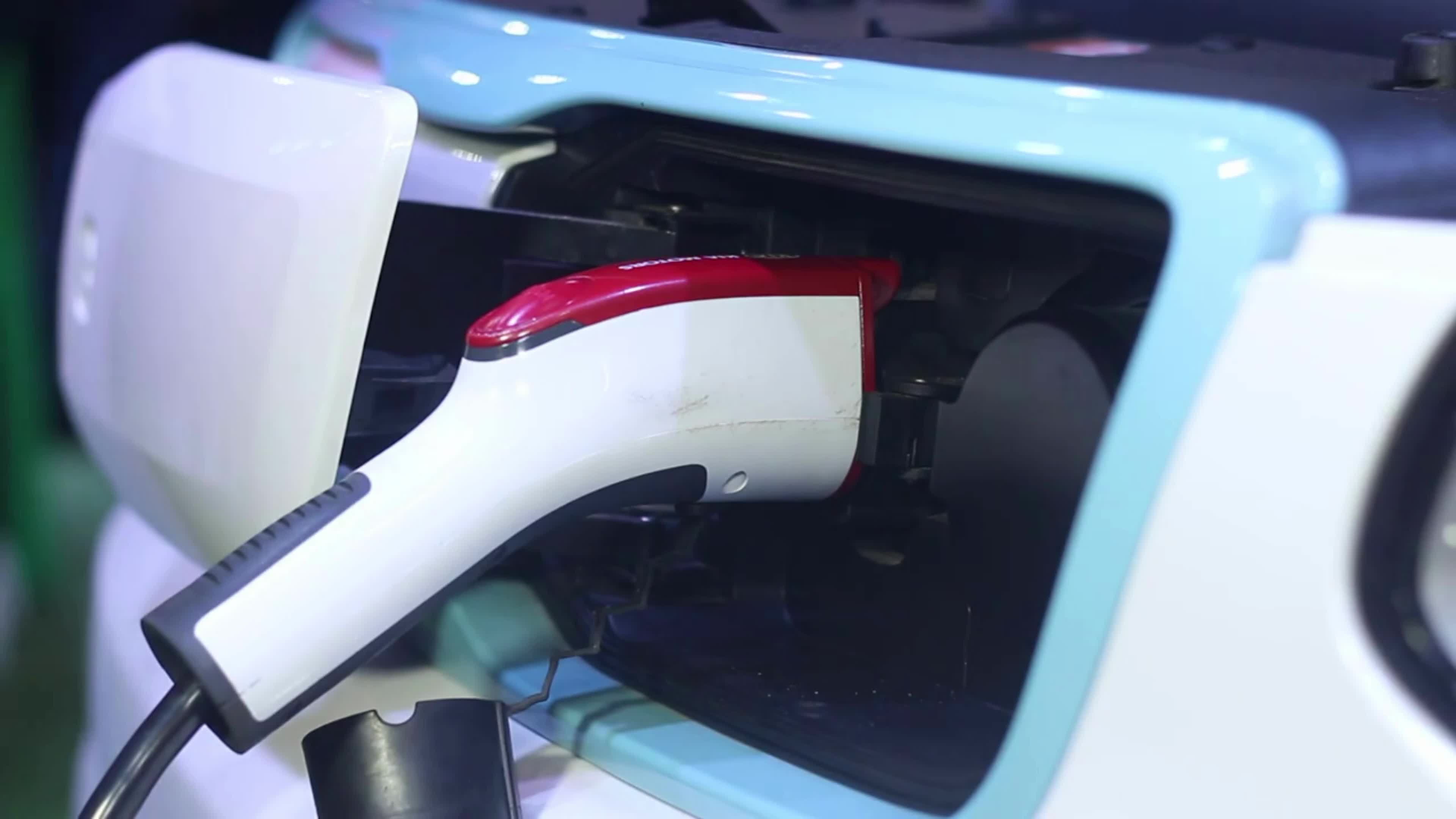 CLOSE UP Opening charging port and plugging electric cable in