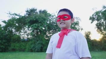 Asian boy wearing hero costume standing and smiling at the park. Going out to the park on the weekend and cover to be a hero. Hero costume concept video