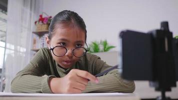 fille asiatique se concentrant sur le fait de regarder une photo au téléphone et de la suivre en dessinant. mettre le téléphone sur la table. rester à la maison le week-end. faire le concept de passe-temps. video