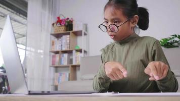 Asian girl studying online and taking video call on laptop in living room.  Sharing idea. Setting laptop on the table and Studying online by laptop concept