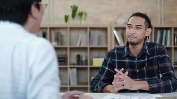 un travailleur masculin qui est un employé présentation et discussion d'idées pour le succès du commerce électronique avec des graphiques commerciaux à un patron asiatique à un bureau dans un petit bureau de démarrage. video