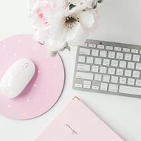 white workspace with light pink note book and white flower with coffee on white table. photo