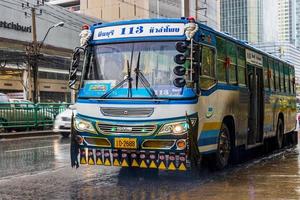 Typical colorful blue decorated bus in heavy rain Bangkok Thailand. photo