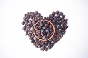 Granos de café en un cuenco de madera con forma de amor foto
