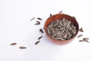 Sunflower seeds in a wooden bowl on a white table photo