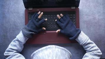 mão do hacker roubando dados do laptop de cima para baixo.