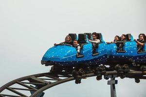Canela, Brazil - July 21, 2019. People in a blue cart having fun on roller coaster in a cloudy day at the Alpen amusement park near Canela. A charming small town very popular by its ecotourism.