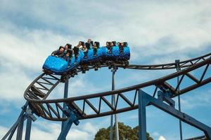 Canela, Brazil - July 21, 2019. People in a blue cart having fun on roller coaster in a cloudy day at the Alpen amusement park near Canela. A charming small town very popular by its ecotourism. photo