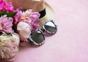 Pink peonies and hat on a pink concrete background photo