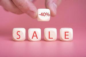 Wooden cubes on a pink background, on them the word SALE is written photo