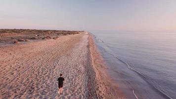 Joven corredor de formación en la hermosa puesta de sol en la playa