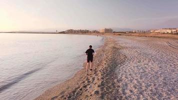 jonge atleet runner man met fit sterk lichaam training op prachtige zonsondergang op het strand video