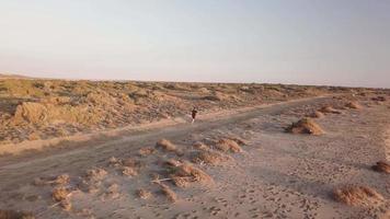 Young man running in the desert landscape video