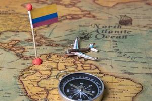 bandera de colombia, brújula y avión en el mapa mundial. foto